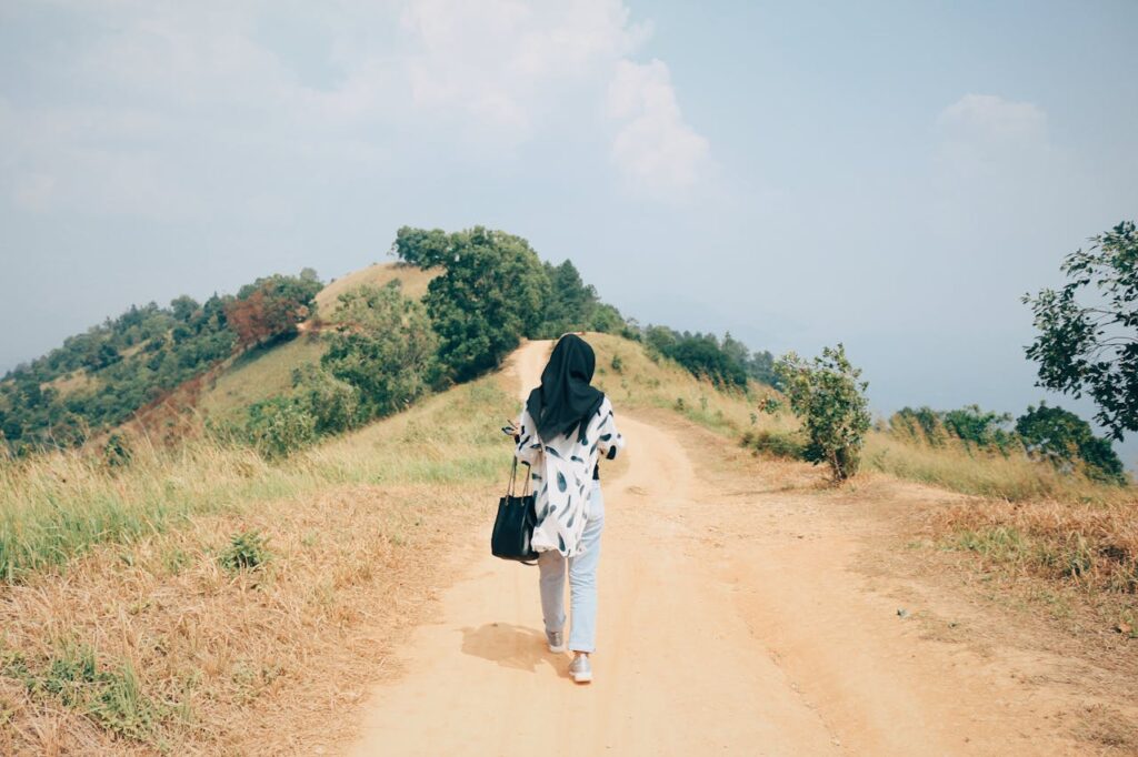 Back View Photo Woman in Black Hijab Walking Alone on Dirt Road